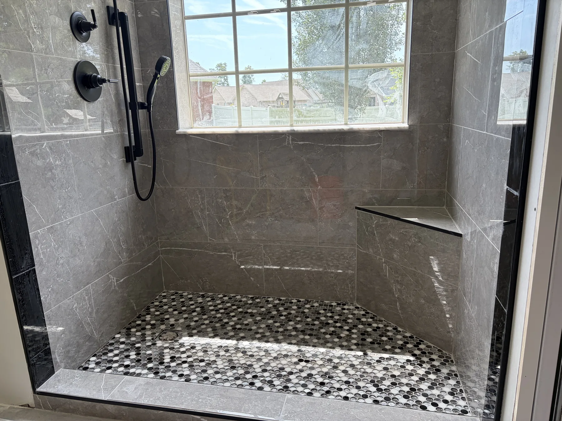 Grey marble-look walk-in shower with built-in bench and penny round mosaic floor